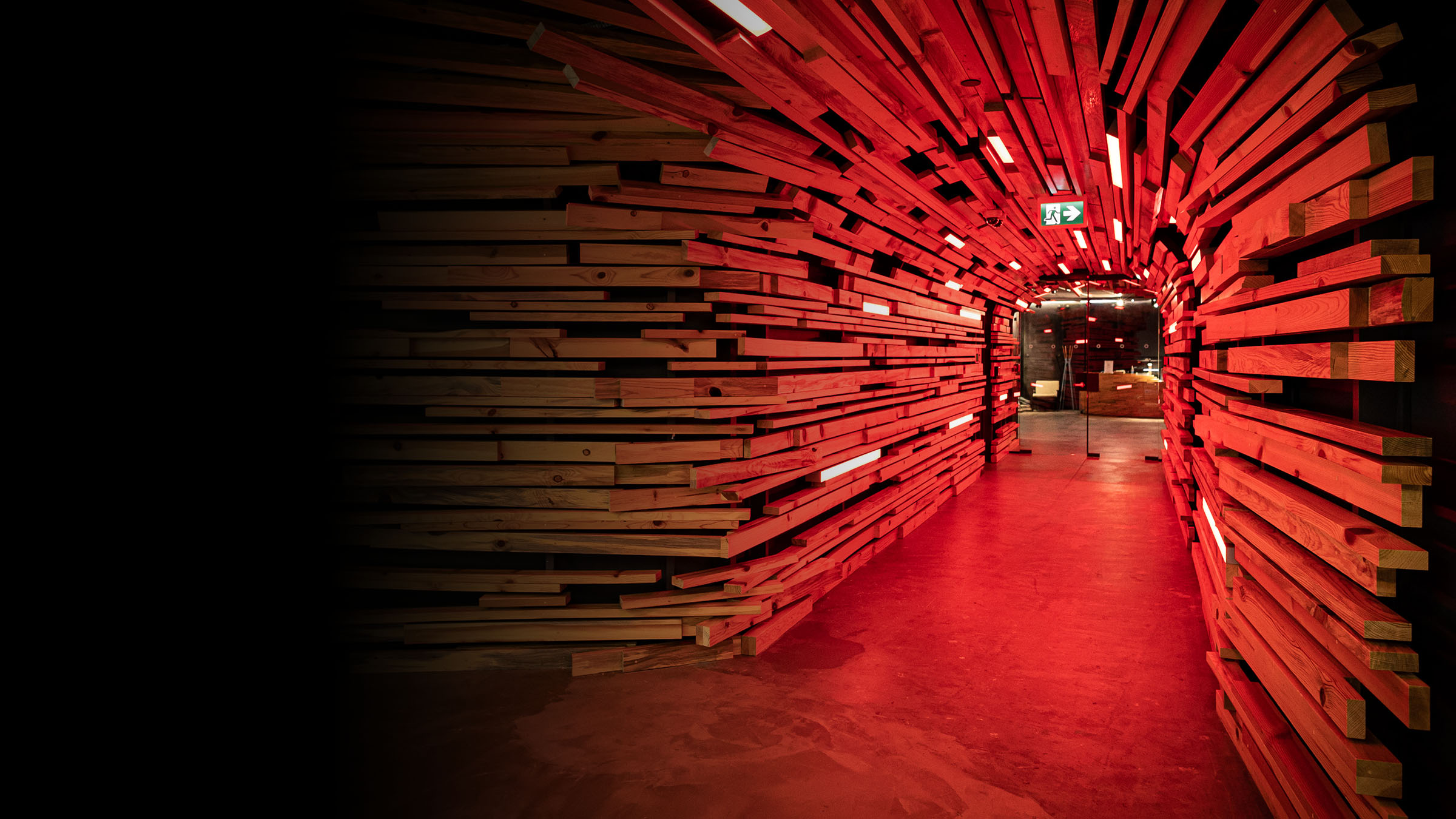 A hallway inside our studio covered in wooden planks and lite with red light.