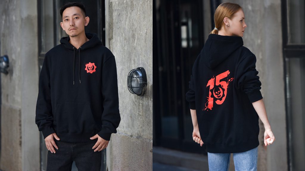 A male and female model showing off the 15th anniversary Gears hoodie in black available through Insert Coin